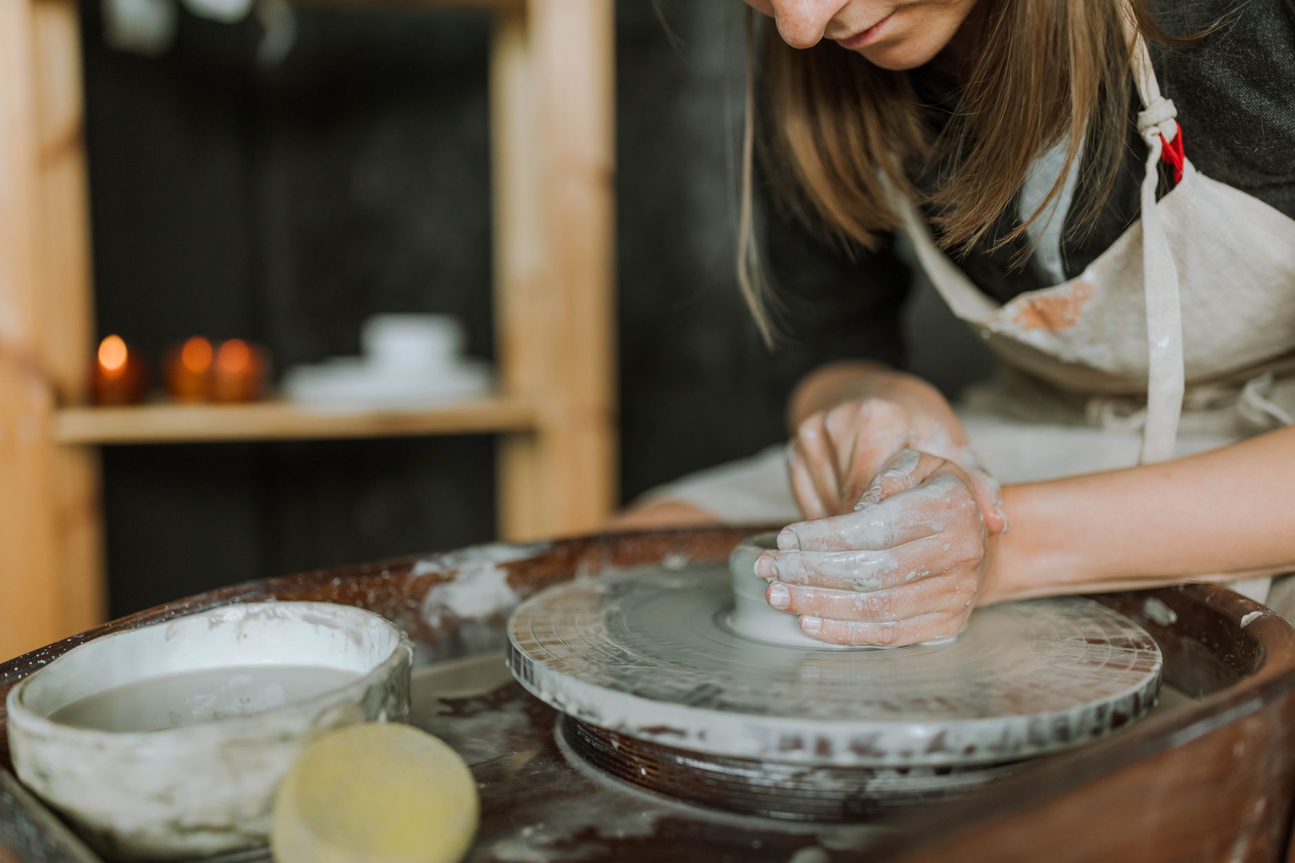Craftswoman shaping clay on a pottery wheel in a studio, showcasing handcrafting art.